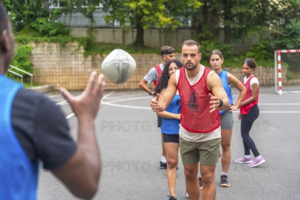 Multi ethnic rugby players engaging in passing drills on an outdoor court within a city park, fostering teamwork, promoting fitness, and exemplifying sportsmanship among athletes