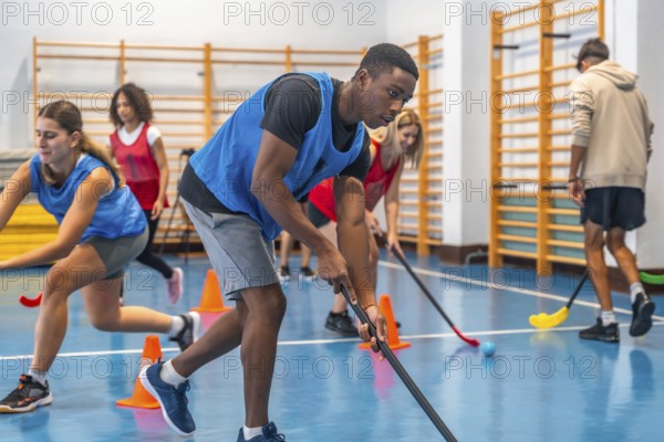 Floorball players sprinting between cones while honing their stick handling skills during a vibrant training session in a well lit gymnasium, showcasing teamwork and athleticism