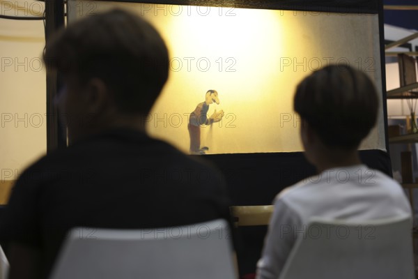 A Syrian puppeteer entertains children at the Damascus International Fair by imitating the role of the Hakawati, a traditional storyteller, while using hand puppets. The performance reflects Syria's cultural heritage and was part of activities organized for young visitors, Damascus, Damascus, Syria