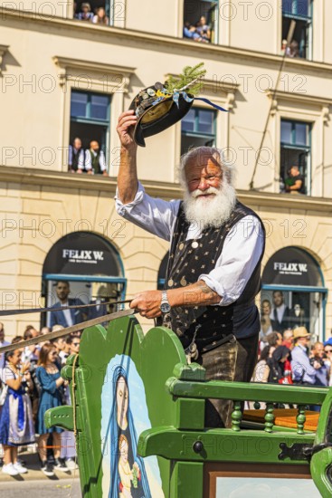 A traditional costumer on a carriage greets the spectators, Trachten- und Schützenzug, Oktoberfest, Munich, Upper Bavaria, Bavaria, Germany