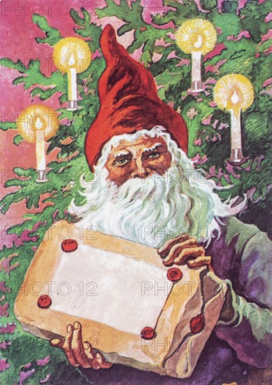 Old greeting Christmas card. Portrait of Santa Claus holding a Christmas present in front of a Christmas tree with lit candles