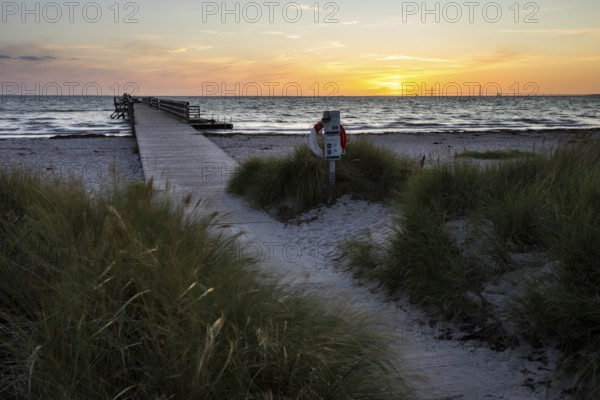 Evening beach dunes and lonely passenger pier at sunset, peaceful sea waves, Kobaek Strand, Sjaelland, Denmark