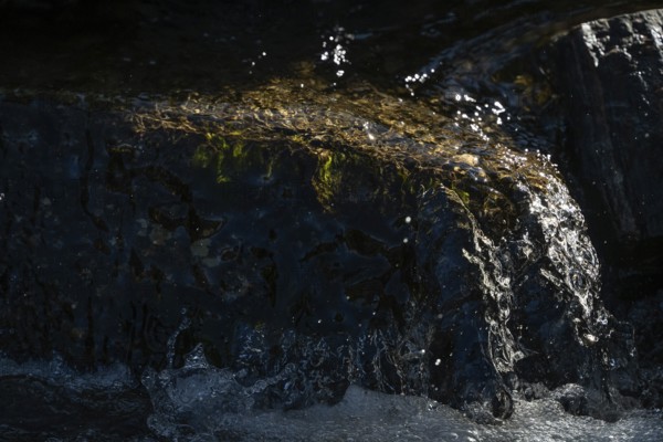 Water of a stream flowing over rocks, light reflections, Otroya or Otrøya island, Møre og Romsdal, Norway