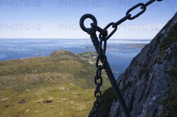 View over coastal landscape with offshore islands, silhouette, hook of a via ferrata in the foreground, island Otroya or Otrøya, Møre og Romsdal, Norway