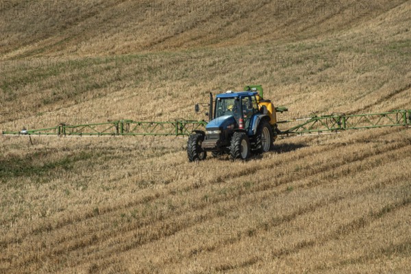 Tractor spreading fertilizer on harvested stubble field in Ystad municipality, Skåne county, Sweden, Scandinavia