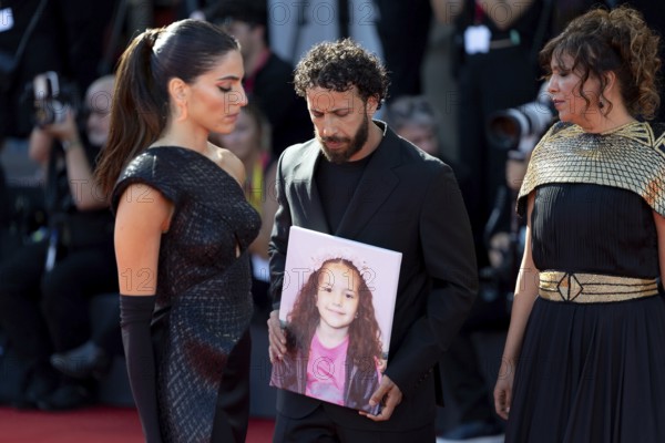 Venice, Italy - 3 September 2025: Kaouther Ben Hania (R) and Saja Kilani (L) and Motaz Malhees (C) with a portrait of five-year-old Palestinian girl Hind Rajab, who was killed by the Israeli army in the Gaza Strip in January 2024, during the Red Carpet of - The Voice Of Hind Rajab - during the 82nd Venice International Film Festival