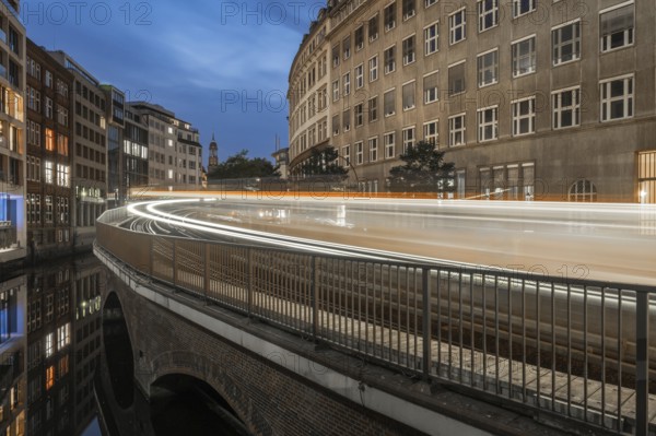 Long exposure at Mönkedamm with underground line U3 and light strip and St Michael's Church in the background at blue hour, Hamburg, Germany
