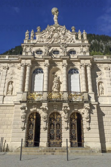 View of portal and façade entrance to Linderhof Palace in the Neurococo style with sculptures made of limestone and cast zinc, at the top of the pediment of the main façade coat of arms of the Kingdom of Bavaria, above it statue of Atlas with celestial globe, Ettal, Bavaria, Germany