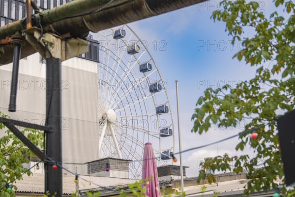 Ferris wheel in an urban environment with plants and hanging lights, Werksviertel Munich, Munich, Germany