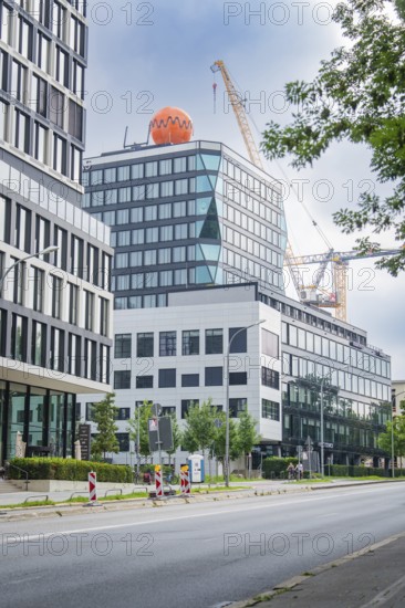 Office complex with neighbouring construction site and crane in the background of a street, Munich, Germany