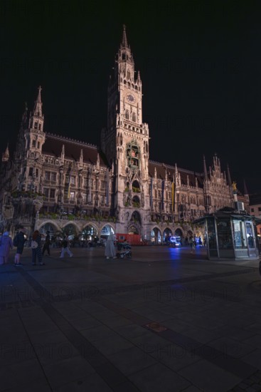 Historic building at night with lighting, people walking around, Munich, Germany