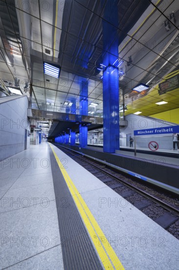 Empty underground station at Münchner Freiheit with blue design and visible tracks, Munich, Germany
