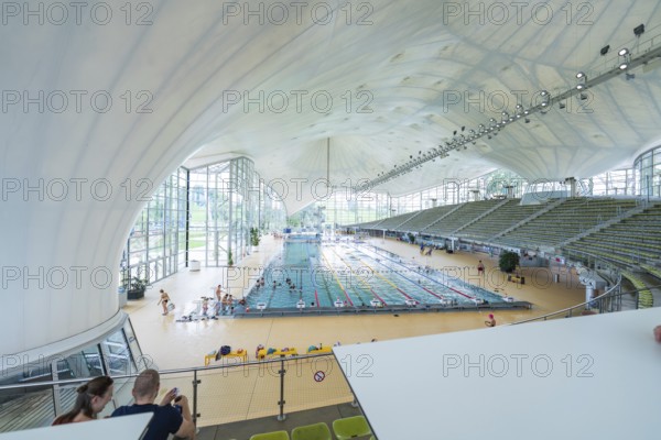 View from above of a modern swimming pool with grandstands and lots of glass, Olympiabad, Munich, Germany