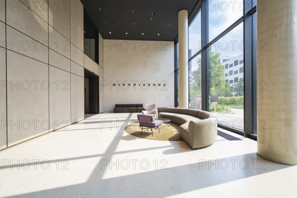Elegant lobby with plenty of sunlight, modern furniture and a large glass wall, Munich, Germany