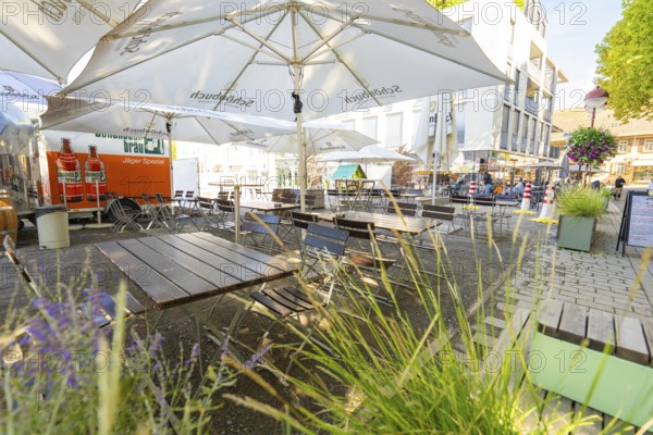 Empty outdoor café with wooden tables, chairs and parasols in a sunny city neighbourhood, Sindelfingen, Böblingen district, Germany