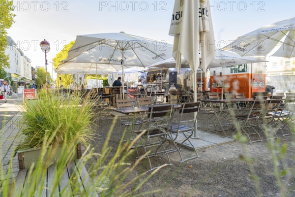 Cosy street café with empty tables and chairs under large parasols, surrounded by green plants, Sindelfingen, Böblingen district, Germany