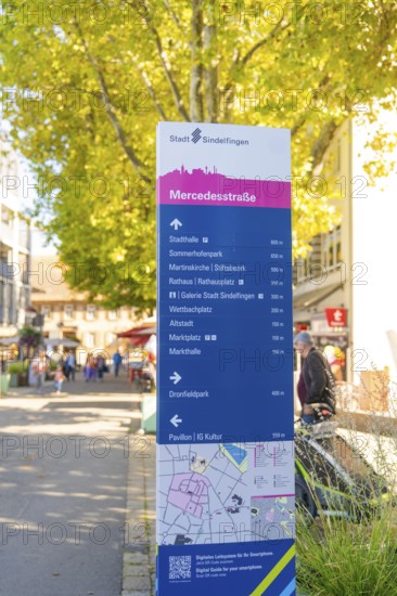 Urban signpost with distances to various destinations in a sunny neighbourhood, Sindelfingen, Böblingen district, Germany
