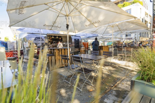 Outdoor area of a snack bar with tables and chairs under parasols, surrounded by plants, Sindelfingen, Böblingen district, Germany