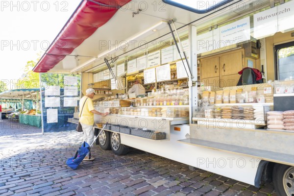 Person standing in front of a mobile market stall with various products, Sindelfingen, Böblingen district, Germany