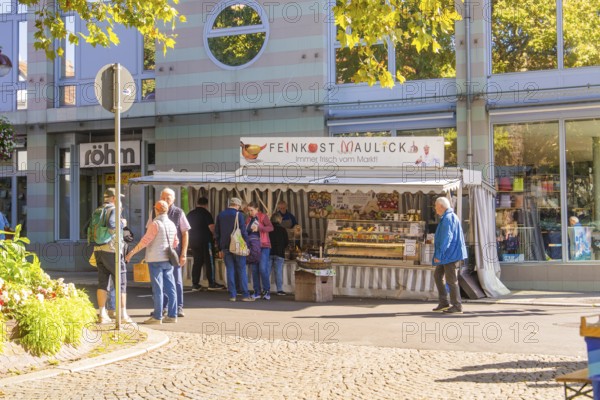 People standing in front of a delicatessen stall surrounded by modern architecture in the city centre, Sindelfingen, Böblingen district, Germany