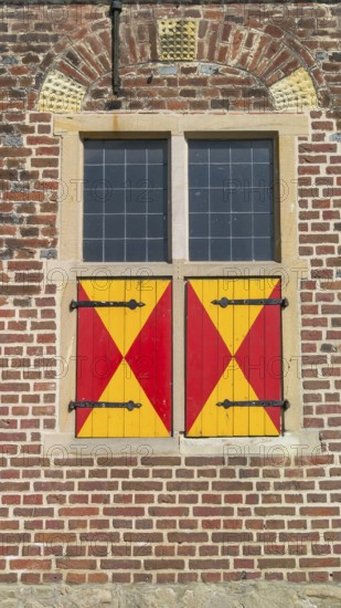 Window with red and yellow shutters on a brick wall, Raesfeld Castle, Münsterland, North Rhine-Westphalia, Germany