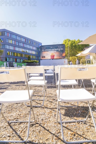 White chairs stand in rows in front of an outdoor screen on a sunny day, open air cinema Sindelfingen, district of böblingen, Germany