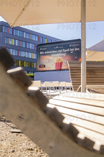 Chairs and screen under parasols with wooden details in a summery setting, open air cinema Sindelfingen, district of böblingen, Germany