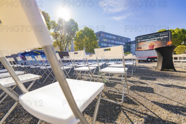 White chairs lined up outside in sunny weather in front of a building and a large screen, open air cinema Sindelfingen, district of böblingen, Germany