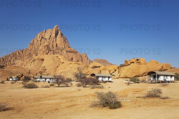 The isolated Spitzkoppe mountain (1728 m) provides a dramatic backdrop for the chalets of the upmarket Spitzkoppen Lodge. Damaraland, Namibia
