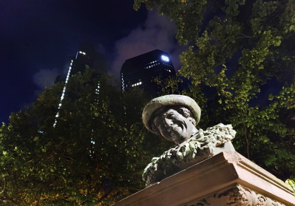 Blessed shall the drink be to us: The water to you and the wine to me, saying on the Lachhannesbrunnen by Johann Nepomuk Zwerger in front of Deutsche Bank at night, Frankfurt am Main, Hesse, Germany
