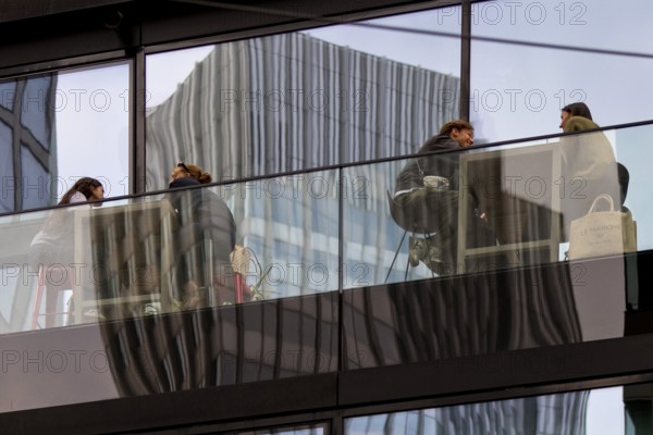 People on the glazed outdoor balcony in a bar with reflection of a skyscraper, Frankfurt am Main, Hesse, Germany