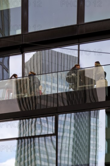 People on the glazed outdoor balcony in a bar with reflection of a skyscraper, Frankfurt am Main, Hesse, Germany