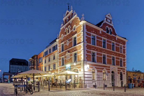 Night shot, magnificent building with outdoor seating and sunshade, built in 1889, Hiddenseer Hafenrestaurant und Hotel, Hafenstraße 12B, harbour island, old town, UNESCO World Heritage Site, Hanseatic City of Stralsund, Mecklenburg-Western Pomerania, Germany