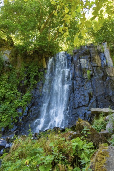 Vaucoux waterfall cascades gracefully over dark rocks, surrounded by lush greenery, Auvergne Volcanoes Regional Park, Puy de Dome., Auvergne-Rhone-Alpes, France