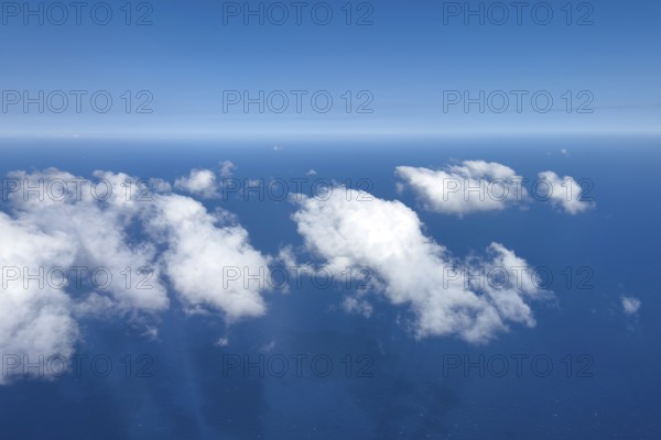 Aerial view from 11000 metres 36, 000 ft feet altitude on white cirrocumulus high cumulus clouds, in the background horizon and blue sky, below blue sea, International