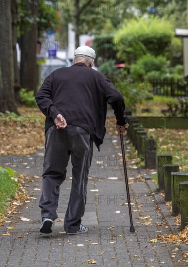 Elderly man going for a walk with the help of a walking stick, North Rhine-Westphalia, Germany