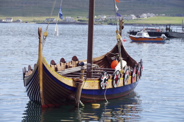 A traditional Viking boat lies decorated in the calm waters of a harbour, Lerwick, Shetland, Shetland Islands, Scotland, United Kingdom