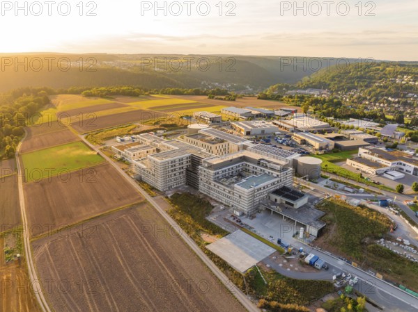 Modern building surrounded by fields and surrounding hills at sunset, new hospital building, Calw health campus, Black Forest, Germany