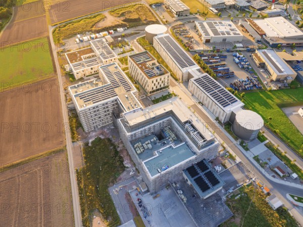 Complex of industrial buildings and fields seen from above in bright sunlight, new hospital building, Calw health campus, Black Forest, Germany