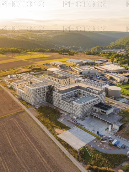 Modern building surrounded by fields and hills at sunset from the air, new hospital building, Calw health campus, Black Forest, Germany