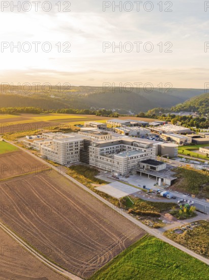 Large building in a rural setting with fields and rolling hills at dusk, new hospital building, Calw Health Campus, Black Forest, Germany