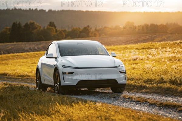 White car on a dirt road in a golden landscape at sunset, Tesla Model Y Juniper, electric car
