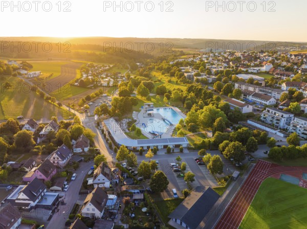 Aerial view of a village with swimming pool and surrounding houses at sunset, small town of Perle Calw, Black Forest, Germany