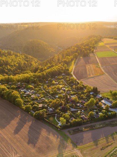 Campsite nestled between fields and wooded hills in the warm sunset light, small town of Perle Calw, Black Forest, Germany