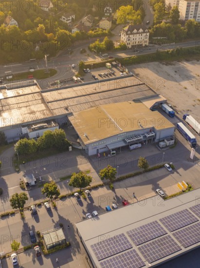 Industrial buildings at dusk with solar panels on the roof and car parks, small town of Perle Nagold, Black Forest, Germany