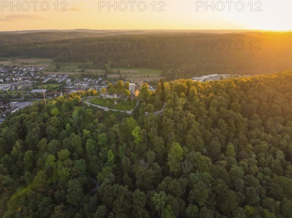 Panoramic shot of a castle ruin in a hilly forest landscape in the warm evening light, small town of Perle Nagold, Black Forest, Germany