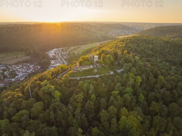 Historic castle ruins surrounded by woods on a hill, illuminated by the last light of the evening, small town of Perle Nagold, Black Forest, Germany