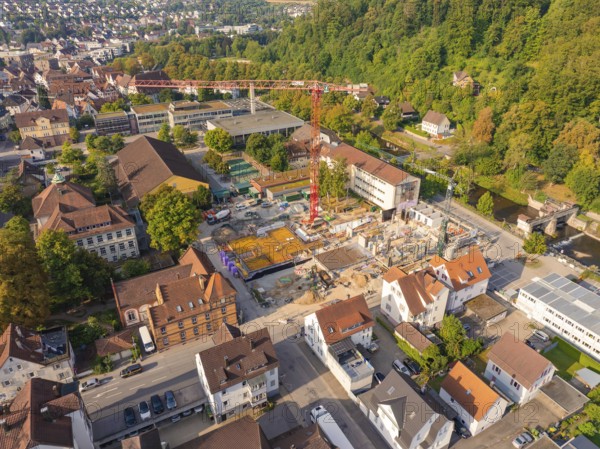 Urban construction site with crane next to old and new buildings in the middle of a green environment, small town Perle Nagold, Black Forest, Germany