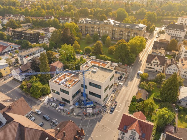 New building in a residential area with crane, surrounded by autumnal colours and streets, small town of Perle Nagold, Black Forest, Germany
