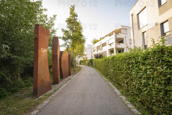 Rustic sculptures along a footpath through modern residential buildings, small town of Perle Nagold, Black Forest, Germany